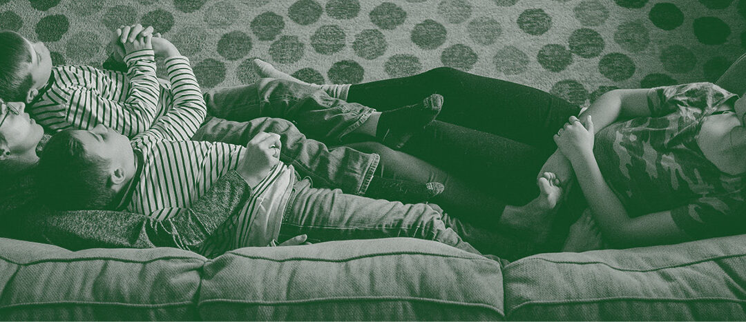 Mutter und Kind auf dem Sofa, erschöpft, aber verbunden, wenn die Familie ständig krank ist