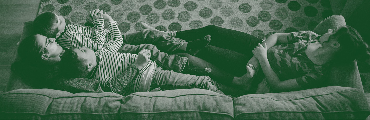 Mutter und Kind auf dem Sofa, erschöpft, aber verbunden, wenn die Familie ständig krank ist